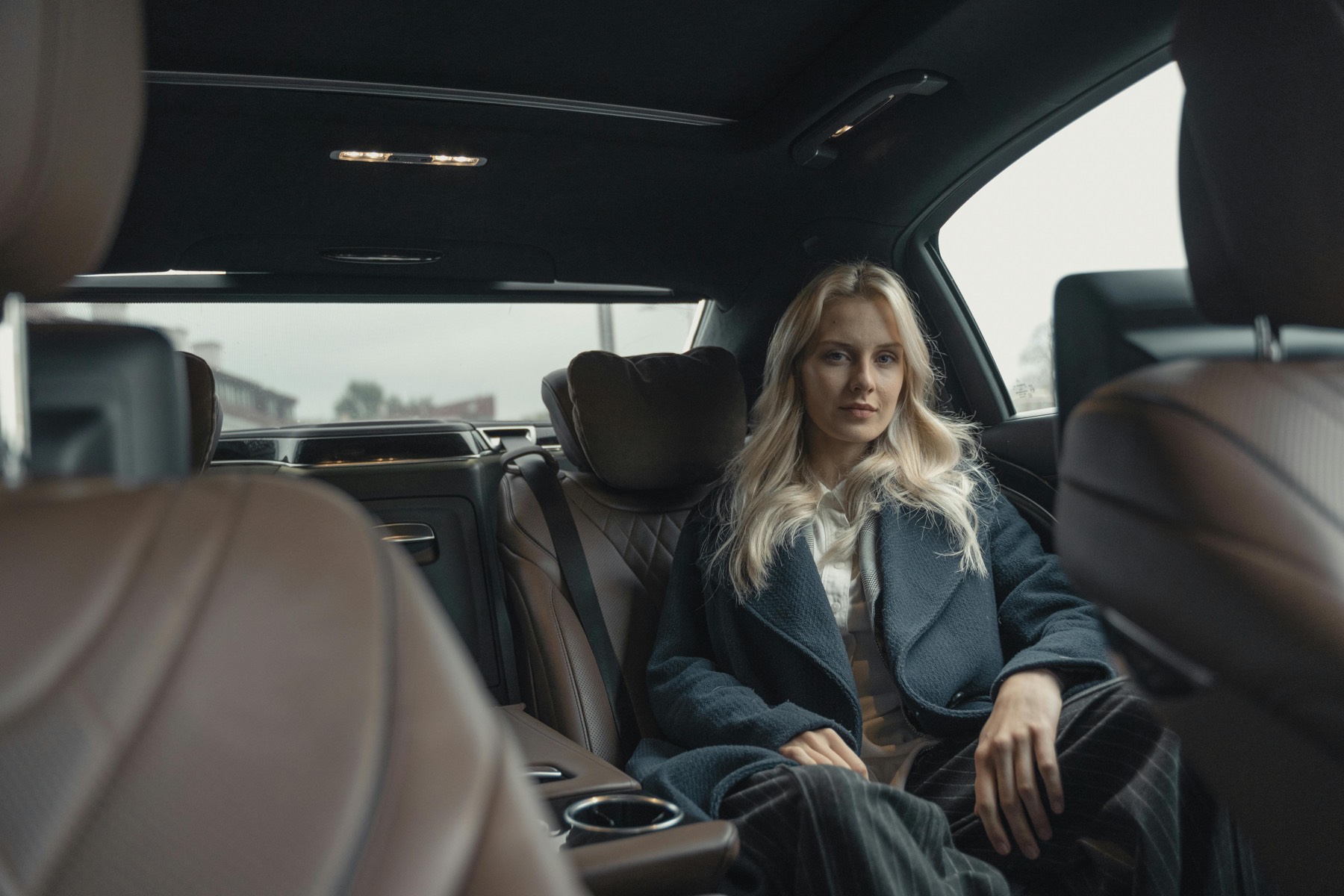 A real estate agent seated in the back of a car on the way to a showing
